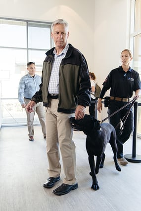 Firearms Detection Canine sniffing man standing in line for firearm