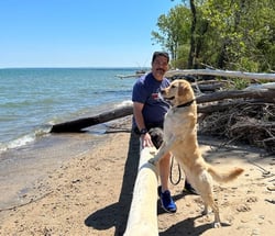 photo of man with yellow labrador at the beach