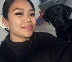 selfie of a woman smiling near a black Labrador