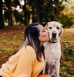 Photo of female handler kissing yellow canine