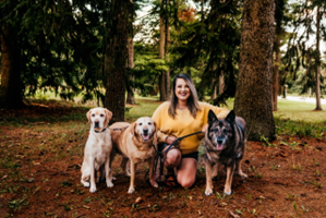 Photo of female handler kneeling with 3 canines