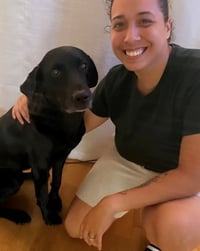 photo of a woman and black lab sitting